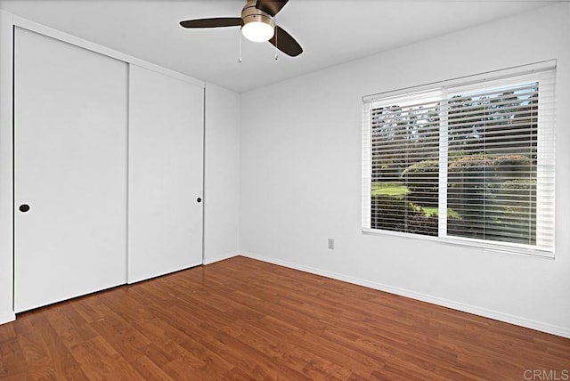 unfurnished bedroom with ceiling fan, a closet, baseboards, and wood finished floors