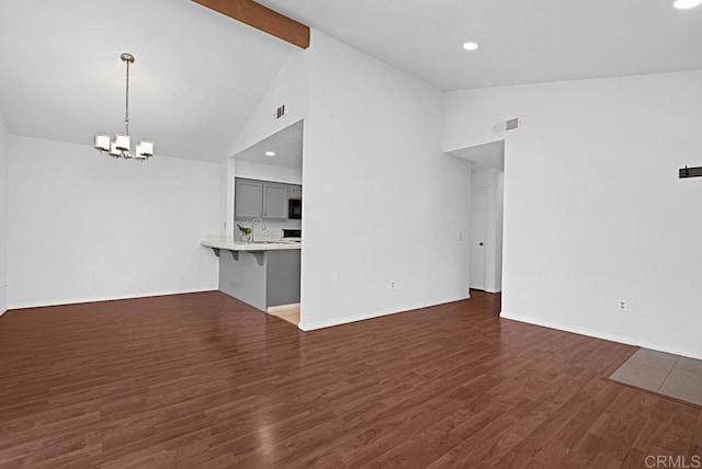 unfurnished living room featuring a notable chandelier, visible vents, wood finished floors, beamed ceiling, and baseboards