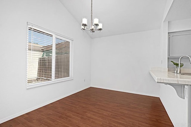 unfurnished dining area with lofted ceiling, a chandelier, dark wood-type flooring, a sink, and baseboards