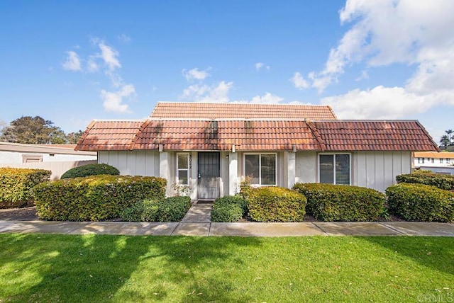 view of front of property featuring a front yard and a tiled roof