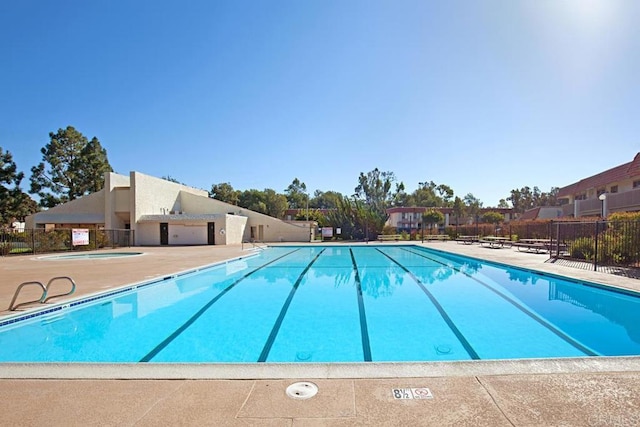 pool with a community hot tub, a patio area, and fence