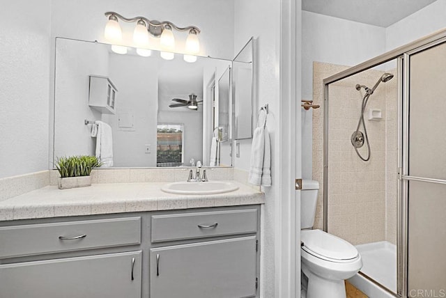 full bathroom with ceiling fan, a stall shower, vanity, and toilet