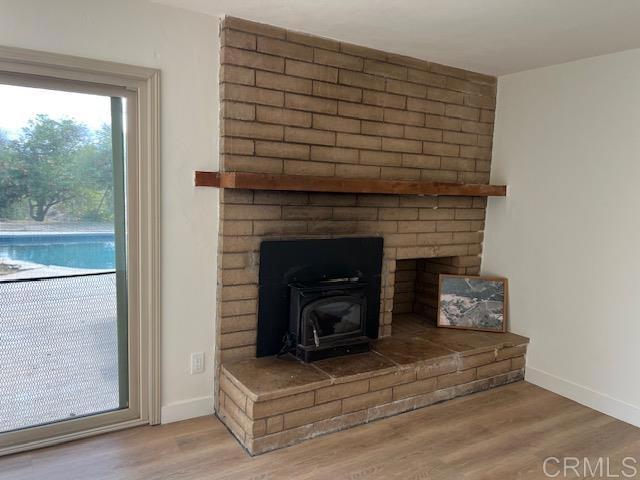 interior details featuring a wood stove, baseboards, and wood finished floors