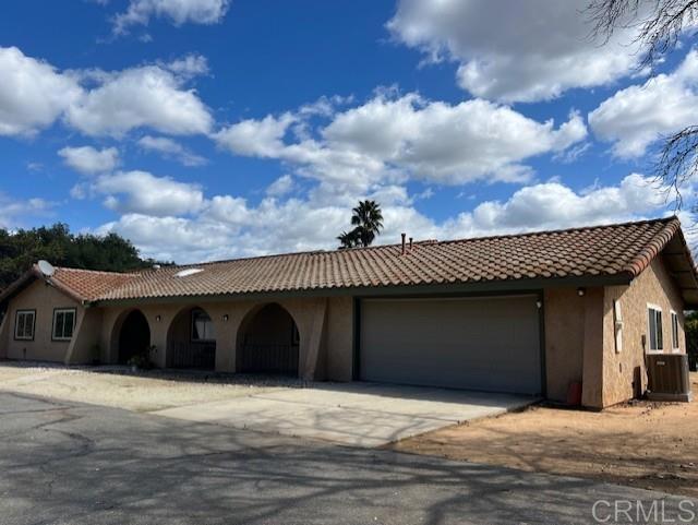 mediterranean / spanish-style home featuring an attached garage, driveway, a tile roof, and stucco siding