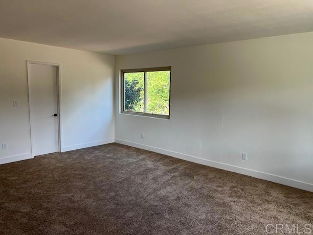 empty room featuring dark carpet and baseboards