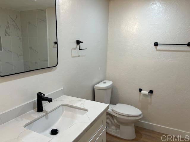 bathroom featuring baseboards, vanity, toilet, and wood finished floors