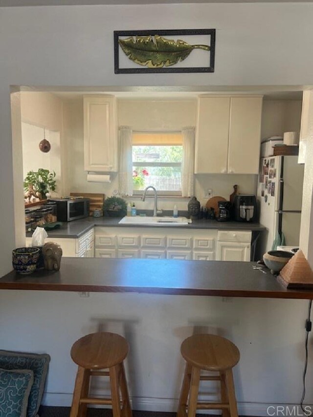 9946 Nutby Ln, Escondido, CA 92026 - kitchen with a sink, a peninsula, freestanding refrigerator, and dark countertops