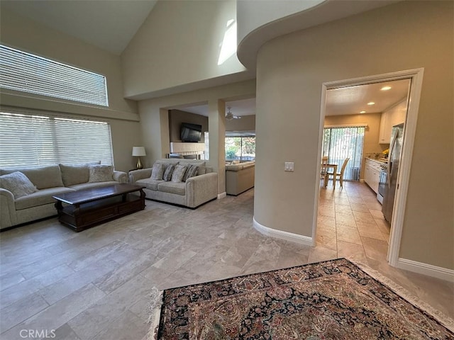 living area with high vaulted ceiling, baseboards, and a wealth of natural light