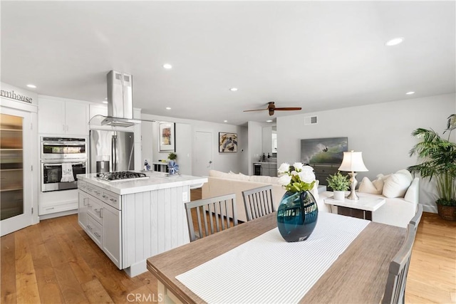 kitchen with a kitchen island, open floor plan, island exhaust hood, and stainless steel appliances