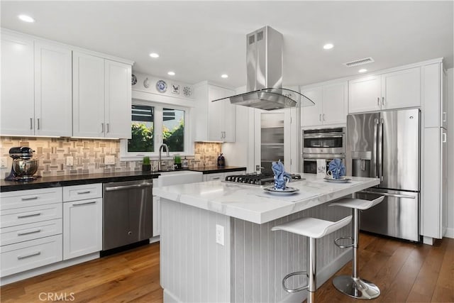 kitchen featuring island exhaust hood, a sink, stainless steel appliances, white cabinets, and a center island