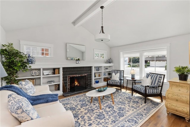 living area featuring a tile fireplace, lofted ceiling with beams, and wood finished floors