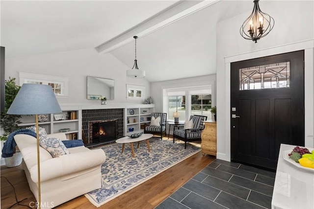 entrance foyer with a tiled fireplace, vaulted ceiling with beams, dark wood-style floors, and a chandelier