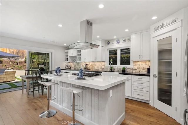 kitchen featuring a sink, plenty of natural light, a kitchen island, and island range hood