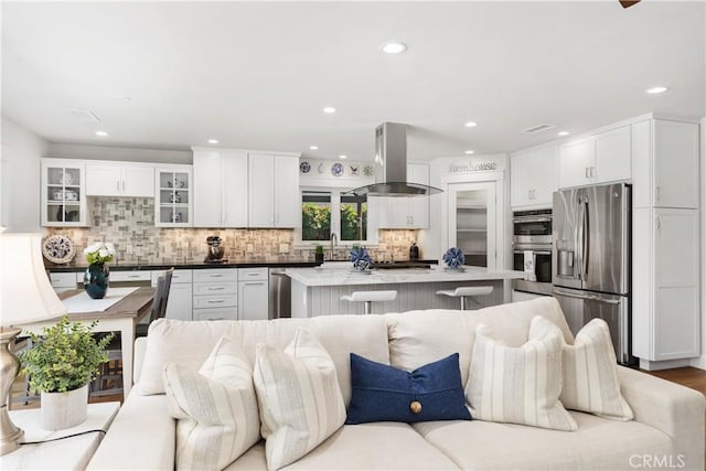 kitchen with a breakfast bar, open floor plan, a center island, appliances with stainless steel finishes, and island range hood