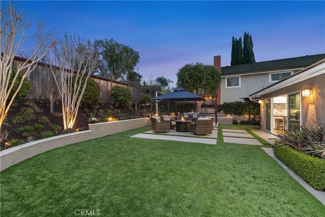 yard at dusk featuring an outdoor living space, a patio, and a fenced backyard