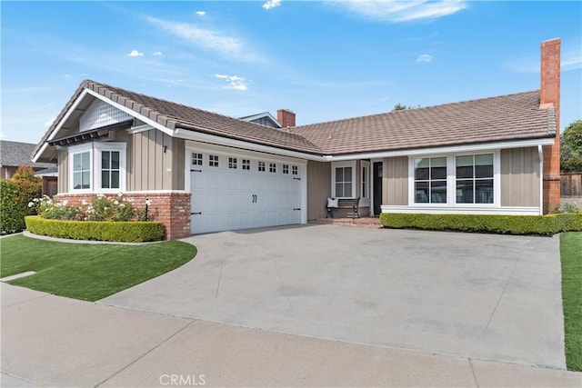 ranch-style home featuring board and batten siding, concrete driveway, a garage, brick siding, and a chimney