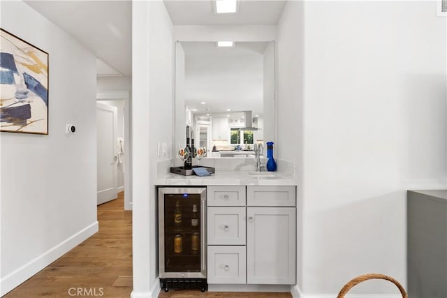 bar with visible vents, baseboards, a sink, wine cooler, and light wood-type flooring