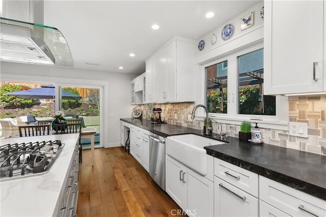 kitchen with decorative backsplash, white cabinetry, appliances with stainless steel finishes, and a sink