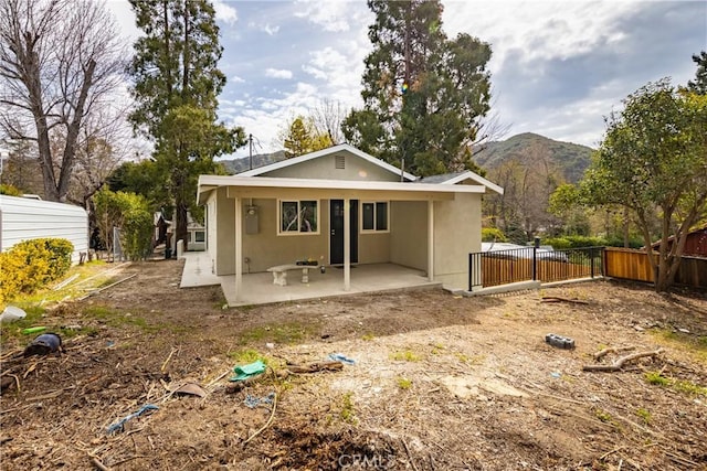 back of property with a patio area, fence, a mountain view, and stucco siding