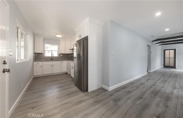 kitchen featuring tasteful backsplash, freestanding refrigerator, white cabinets, and light wood finished floors