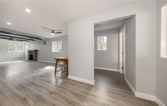 interior space with ceiling fan, a stone fireplace, and wood finished floors