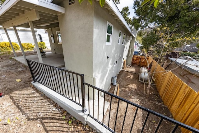 view of home's exterior with a patio area, fence, and stucco siding