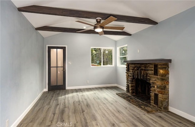 unfurnished living room with a fireplace, vaulted ceiling with beams, ceiling fan, wood finished floors, and baseboards