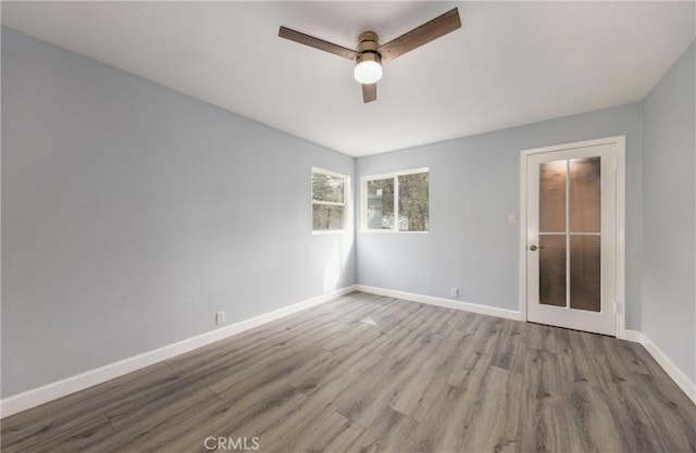 unfurnished room with wood finished floors, a ceiling fan, and baseboards