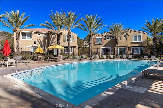 community pool with a residential view, a patio, and fence