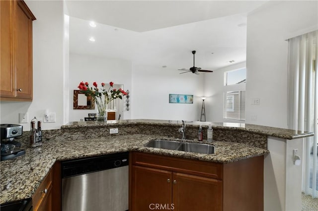 kitchen with a sink, dark stone counters, a peninsula, dishwasher, and ceiling fan