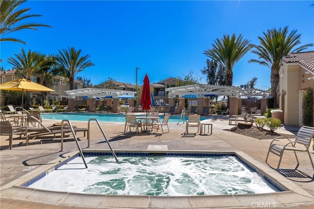 community pool with a pergola, a patio area, fence, and a hot tub