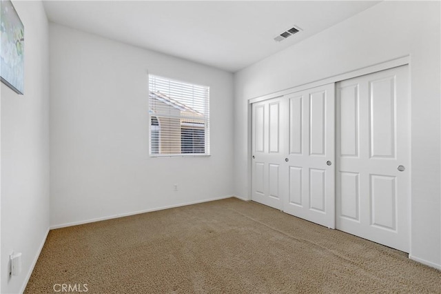 unfurnished bedroom featuring a closet, visible vents, carpet flooring, and baseboards