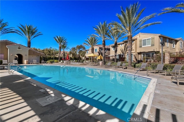 pool with a residential view, a patio, and fence