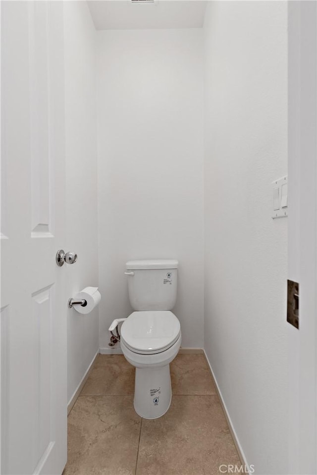 bathroom featuring tile patterned flooring, toilet, and baseboards