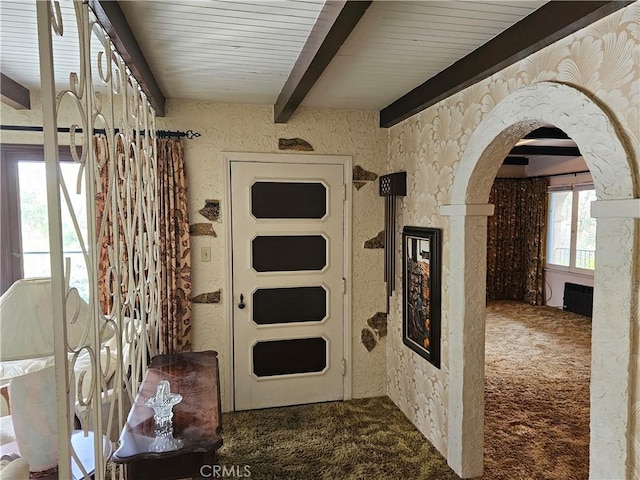 hallway with arched walkways, carpet flooring, and beam ceiling