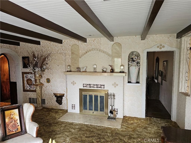 unfurnished living room featuring wallpapered walls, arched walkways, a glass covered fireplace, carpet flooring, and beam ceiling