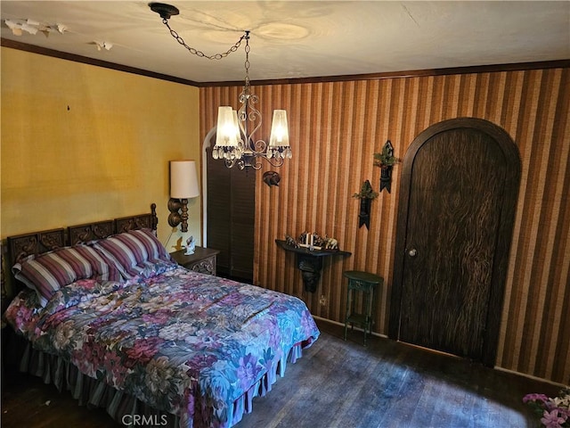 bedroom with wallpapered walls, ornamental molding, wood finished floors, and a notable chandelier