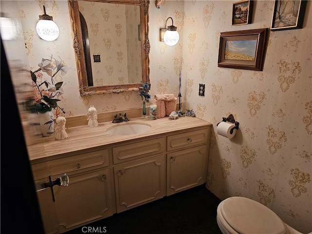 bathroom with vanity, toilet, and wallpapered walls