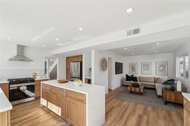 kitchen with stainless steel appliances, light countertops, visible vents, and wall chimney range hood