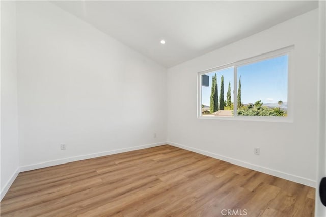 unfurnished room featuring lofted ceiling, light wood finished floors, baseboards, and recessed lighting