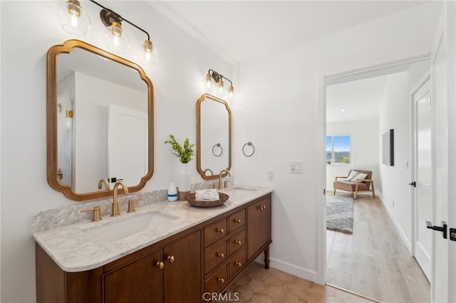 full bathroom featuring a sink, baseboards, and double vanity