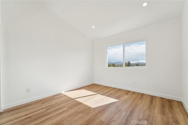 unfurnished room with light wood-style floors, recessed lighting, vaulted ceiling, and baseboards