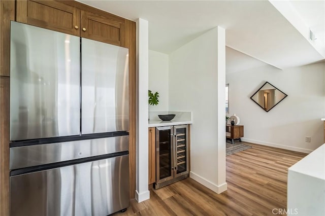 bar featuring wine cooler, visible vents, freestanding refrigerator, wood finished floors, and baseboards