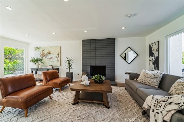 living area featuring light wood finished floors, a brick fireplace, and recessed lighting