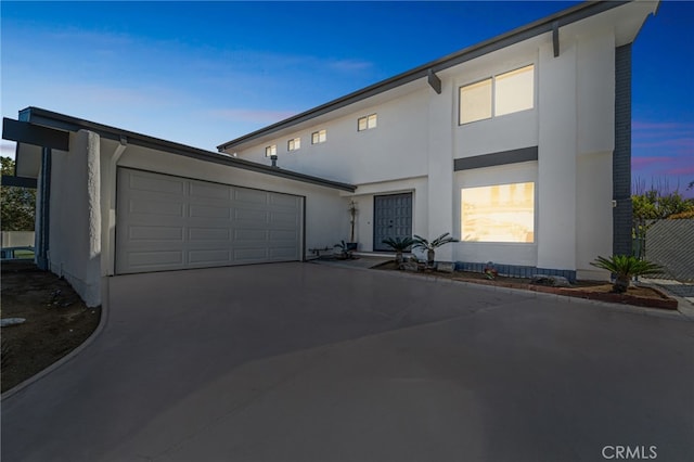 view of front of property with a garage, concrete driveway, and stucco siding