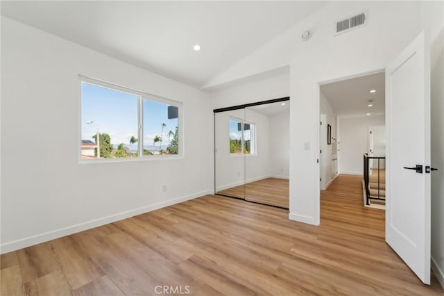 unfurnished bedroom featuring visible vents, vaulted ceiling, light wood-style flooring, and baseboards