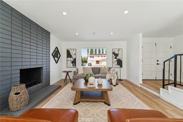 living area featuring a large fireplace, stairway, wood finished floors, and recessed lighting