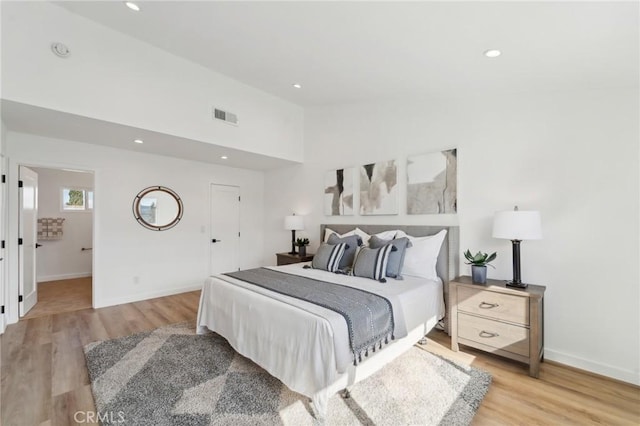 bedroom with baseboards, light wood finished floors, visible vents, and recessed lighting