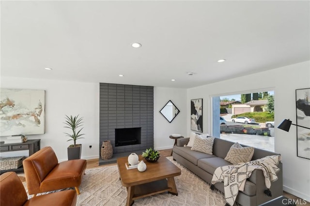 living room featuring light wood-type flooring, a fireplace, baseboards, and recessed lighting