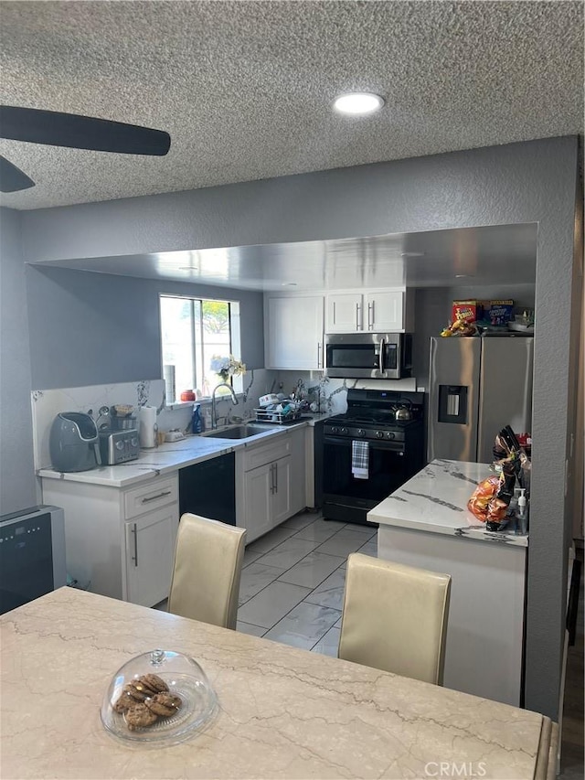 kitchen with appliances with stainless steel finishes, marble finish floor, white cabinetry, and a sink